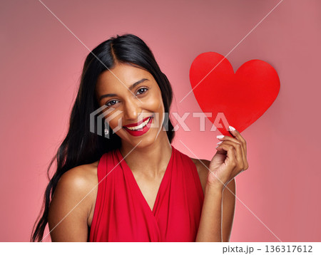 Portrait, heart and smile with a woman on a pink background in studio for love or romance. Valentines day, emoji and social media with a happy young female holding a shape or symbol of affection 136317612