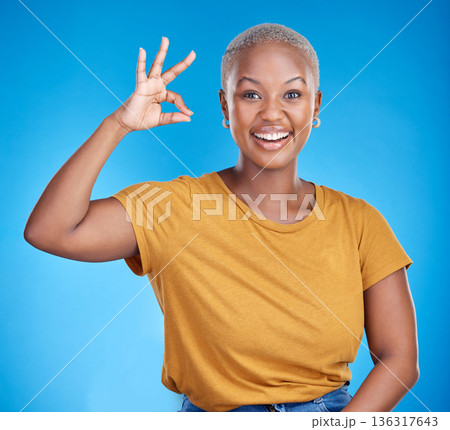 Black woman, ok sign and smile in studio portrait for good review, vote and icon by blue background. African gen z girl, young student and hand for emoji, symbol and happy for feedback, like and yes Black woman, ok sign and smile in studio portrait for good review, vote and icon by blue background. African gen z girl, young student and hand for emoji, symbol and happy for feedback, like and yes 136317643