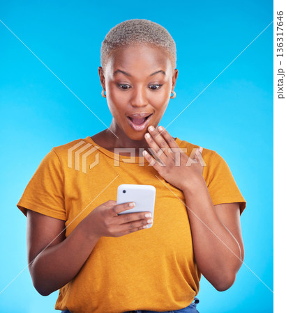 Studio, phone and black woman surprise over reading announcement, winner notification or online sales news. Discount promotion, smartphone information and shocked African person on blue background Studio, phone and black woman surprise over reading announcement, winner notification or online sales news. Discount promotion, smartphone information and shocked African person on blue background 136317646