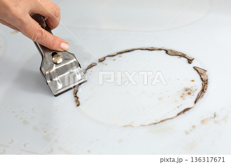 Woman cleaning electronic ceramic stove surface using special steel scraper Woman cleaning electronic ceramic stove surface using special steel scraper 136317671