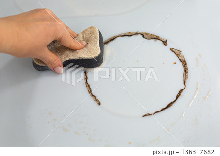 Woman cleaning electronic ceramic stove surface using sponge 136317682