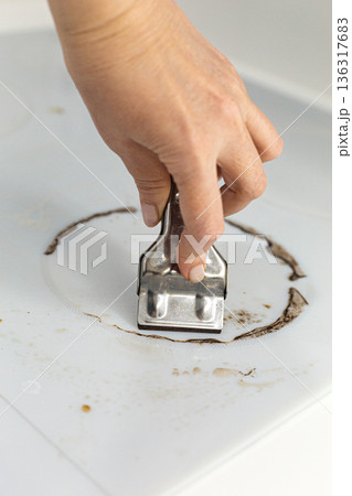 Woman cleaning electronic ceramic stove surface using special steel scraper Woman cleaning electronic ceramic stove surface using special steel scraper 136317683