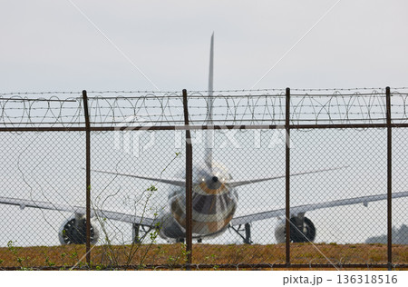 A huge passenger plane pulls onto the runway of Thailand airport, a view through the fence 136318516