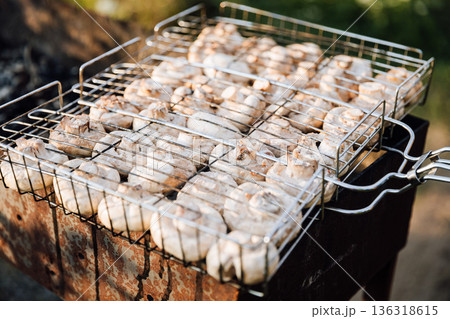Mushrooms roasting in grill basket on barbecue, outdoor cooking at sunset Mushrooms roasting in grill basket on barbecue, outdoor cooking at sunset 136318615