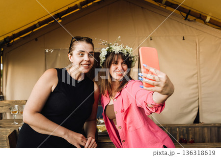 Friends taking selfie at summer glamping party, one wearing flower crown Friends taking selfie at summer glamping party, one wearing flower crown 136318619