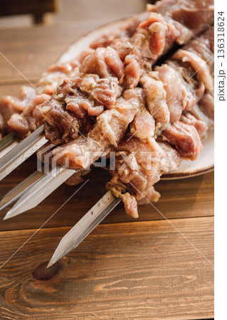 Raw marinated meat on metal skewers on wooden table, barbecue preparation closeup Raw marinated meat on metal skewers on wooden table, barbecue preparation closeup 136318624