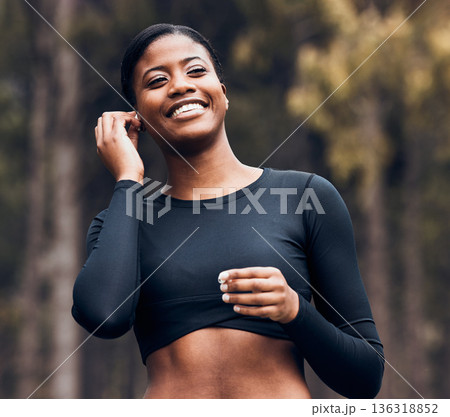 Fitness, black woman listening to music and in nature with earphones happy for training. Exercise or workout, marathon and cheerful female athlete listen to radio or podcast for motivation in forest Fitness, black woman listening to music and in nature with earphones happy for training. Exercise or workout, marathon and cheerful female athlete listen to radio or podcast for motivation in forest 136318852