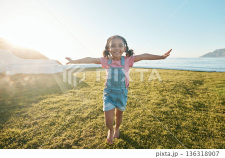 Happy, flying and portrait of girl in park with open arms excited with big smile, freedom and adventure. Childhood, happiness and young child running on grass for playing, relaxing and fun in nature 136318907