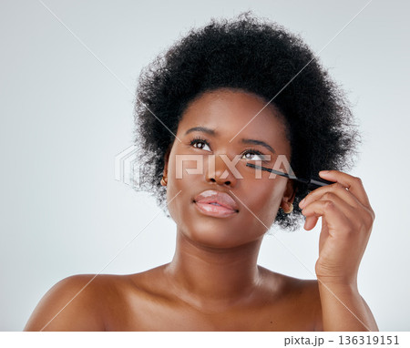 Black woman, makeup and brush for mascara or beauty with afro against a white background in studio. Face of African person or model applying eye product, cosmetics or lashes for facial treatment Black woman, makeup and brush for mascara or beauty with afro against a white background in studio. Face of African person or model applying eye product, cosmetics or lashes for facial treatment 136319151