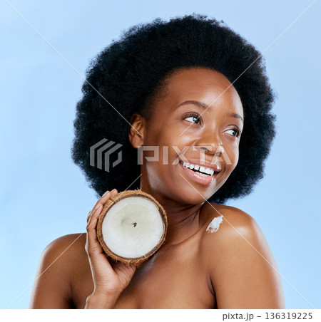 Beauty, skin and coconut with a model black woman in studio on a blue background for natural treatment. Thinking, skincare and cosmetics with a happy young female person holding fruit for oil Beauty, skin and coconut with a model black woman in studio on a blue background for natural treatment. Thinking, skincare and cosmetics with a happy young female person holding fruit for oil 136319225