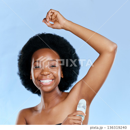 Face, deodorant and armpit of black woman in studio isolated on a blue background. Portrait, underarm and happy model with roll on product for cosmetics, cleaning and hygiene, wellness or fresh scent Face, deodorant and armpit of black woman in studio isolated on a blue background. Portrait, underarm and happy model with roll on product for cosmetics, cleaning and hygiene, wellness or fresh scent 136319240