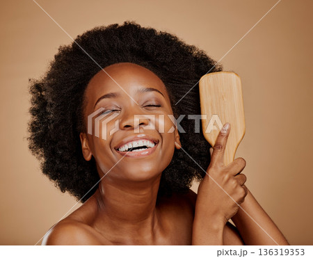 Happy black woman, brush and hair care in studio, brown background and treatment of curly texture. Natural beauty, smile and face of young african female model comb clean, healthy or afro hairstyle Happy black woman, brush and hair care in studio, brown background and treatment of curly texture. Natural beauty, smile and face of young african female model comb clean, healthy or afro hairstyle 136319353