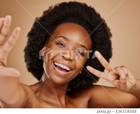 Face, black woman and selfie, peace sign and beauty in studio isolated on a brown background. Portrait, v hand and excited African model taking profile picture with natural cosmetics for skincare. Face, black woman and selfie, peace sign and beauty in studio isolated on a brown background. Portrait, v hand and excited African model taking profile picture with natural cosmetics for skincare. 136319388