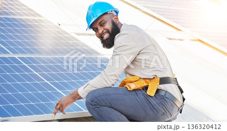 Black man, portrait and technician in solar panel installation on rooftop in city for renewable energy. Happy African male person, engineer or contractor working on roof in sun for electricity power Black man, portrait and technician in solar panel installation on rooftop in city for renewable energy. Happy African male person, engineer or contractor working on roof in sun for electricity power 136320412