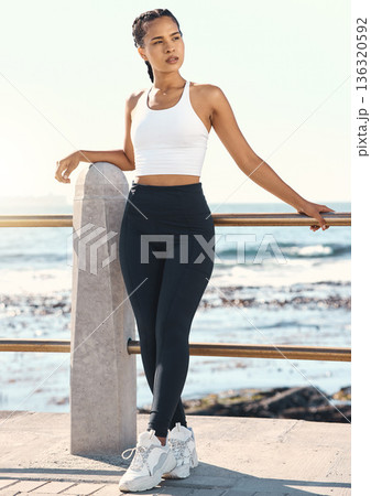 Fitness, woman at beach and training in sportswear for health wellness. Exercise or workout with athlete, thinking or blue sky and female person at the promenade in the morning for sports motivation 136320592