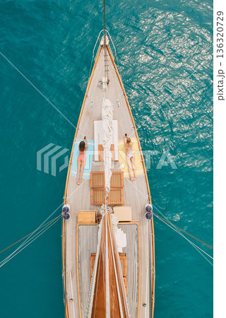 Aerial, ocean and women with phone on boat relax for cruise, luxury sailing and transport on sea. Social media, travel and female people on yacht for tropical journey, sunbathing and tourism on water 136320729