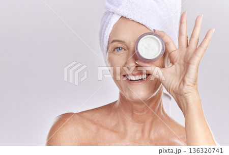 Portrait, mature or happy woman with face cream, towel or beauty in studio isolated on white background. Dermatology creme, smile or senior lady with clean facial skincare cosmetics or glowing shine 136320741