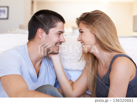 Love, smile and couple relax and bond on a sofa with care, sweet and touching face in their home together. Intimacy, romance and woman with man in a living room happy, chilling and enjoy relationship 136320881
