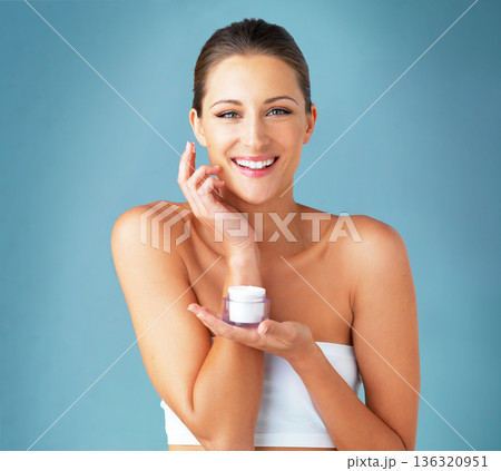 Skincare, cosmetics and portrait of happy woman with cream, dermatology and product on blue background. Lotion, skin care and wellness, model with smile, beauty treatment and facial glow in studio. Skincare, cosmetics and portrait of happy woman with cream, dermatology and product on blue background. Lotion, skin care and wellness, model with smile, beauty treatment and facial glow in studio. 136320951
