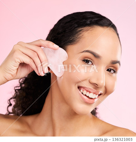 Gua sha, face massage and woman with natural beauty, skin glow and cosmetics. Portrait of a young aesthetic female model happy with self care, facial or dermatology results on a pink background Gua sha, face massage and woman with natural beauty, skin glow and cosmetics. Portrait of a young aesthetic female model happy with self care, facial or dermatology results on a pink background 136321003