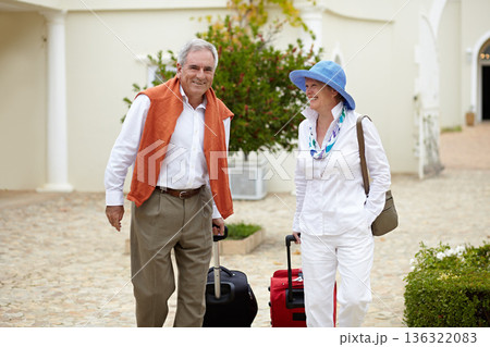 Travel, suitcase and elderly couple walking on vacation in a holiday location happy in retirement together by a hotel. Bag, smile and senior people on a journey or man and woman walk in happiness Travel, suitcase and elderly couple walking on vacation in a holiday location happy in retirement together by a hotel. Bag, smile and senior people on a journey or man and woman walk in happiness 136322083