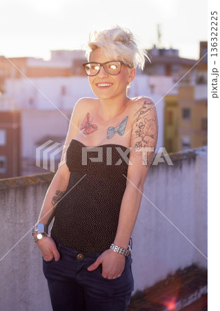 Portrait, stylish and woman on rooftop with tattoos, unique style and creativity in the city. Trendy, creative and a punk lady with fashionable, cool and urban clothes for fashion and summer Portrait, stylish and woman on rooftop with tattoos, unique style and creativity in the city. Trendy, creative and a punk lady with fashionable, cool and urban clothes for fashion and summer 136322225