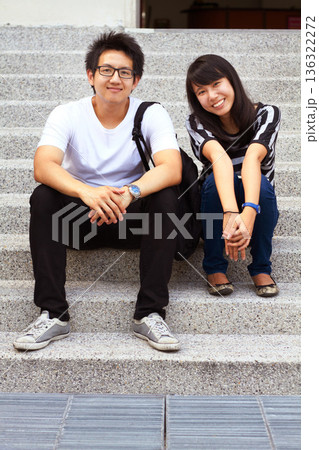 Portrait, education and an asian couple on steps, sitting outdoor at university together for learning. Love, study or college with a man and woman student on stairs to relax while bonding at break 136322272