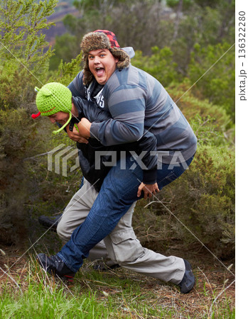 Piggy back, fun and man friends outdoor camping in nature playing and having fun together. Happy, smile and silly portrait of youth and men laughing in the forest on summer camp holiday by trees Piggy back, fun and man friends outdoor camping in nature playing and having fun together. Happy, smile and silly portrait of youth and men laughing in the forest on summer camp holiday by trees 136322280