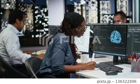 Programmer taking notes at desk in Silicon Valley company office, developing apps. IT expert using machine learning to do coding, writing on notepad, debugging applications to resolve issues 136322896