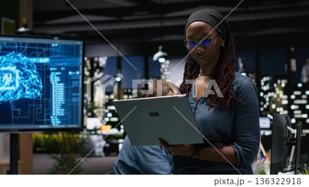 Female technician in office using laptop, working to fix bugs in artificial intelligence system. Woman troubleshooting neural network errors with notebook in tech agency workplace Female technician in office using laptop, working to fix bugs in artificial intelligence system. Woman troubleshooting neural network errors with notebook in tech agency workplace 136322918