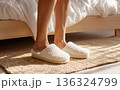 Woman feet in cozy slippers stepping onto jute rug, warm morning comfort and home lifestyle concept 136324799