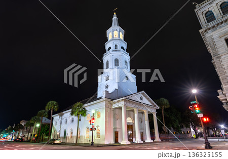 St Michaels Church in Charleston, South Carolina, USA. Historic white colonial architecture features a tall steeple and portico on Broad Street at night 136325155