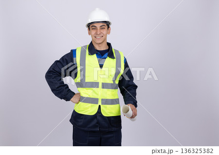 Confident builder in safety vest and helmet smiling Confident builder in safety vest and helmet smiling 136325382