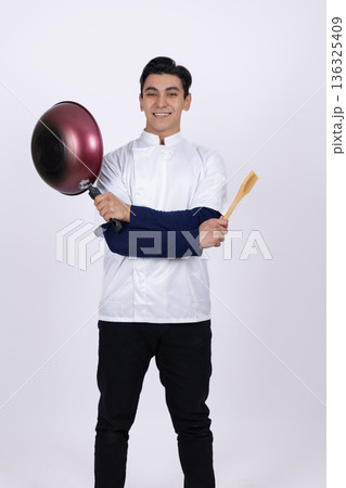 Chef holding pan and looking at it with concentration Chef holding pan and looking at it with concentration 136325409