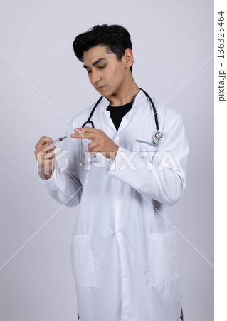 Male doctor in white coat preparing medical syringe 136325464
