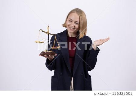 Businesswoman in suit holding justice scales in studio 136325503
