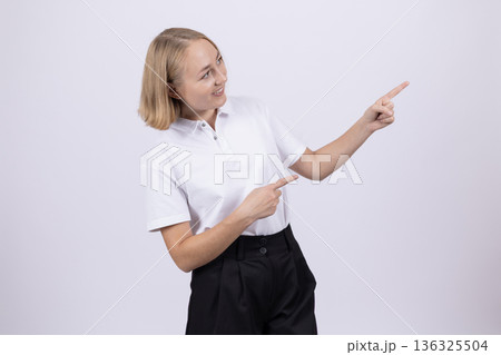 Young woman in white shirt pointing to the side 136325504