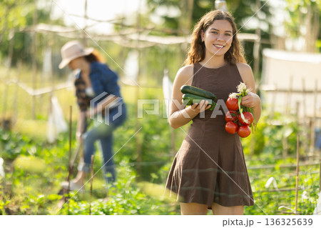 Young woman with vegetable harvest in cottage garden 136325639