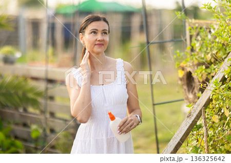 Using mosquito repellent - woman applying mosquito repellent to skin 136325642