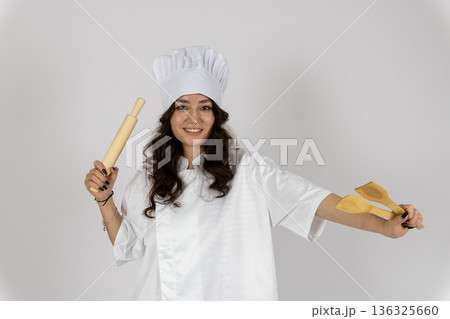 Female chef posing with rolling pin and spatula Female chef posing with rolling pin and spatula 136325660