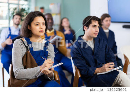 Young female worker listens and takes notes in lecture hall 136325691
