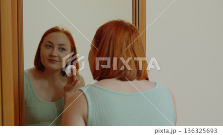 Close up of woman using cotton pad for face cleaning Close up of woman using cotton pad for face cleaning 136325693