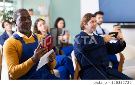 African man worker take photos of presentation slide or scan QR code in classroom African man worker take photos of presentation slide or scan QR code in classroom 136325726