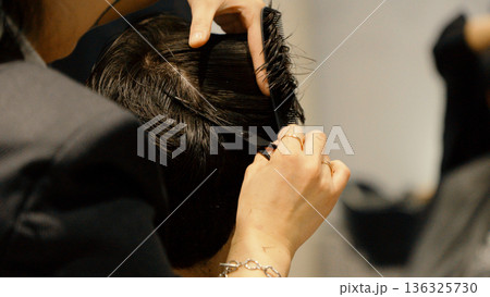 Close up of barber's hands performing hair styling Close up of barber's hands performing hair styling 136325730
