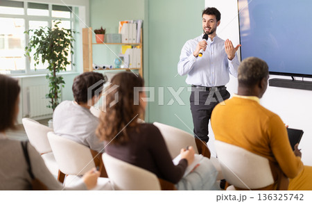 During lesson, man in shirt teacher tells material and gives lecture During lesson, man in shirt teacher tells material and gives lecture 136325742