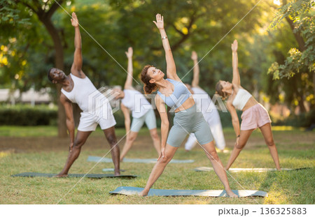 Woman performing Triangle Pose during outdoor yoga practice 136325883