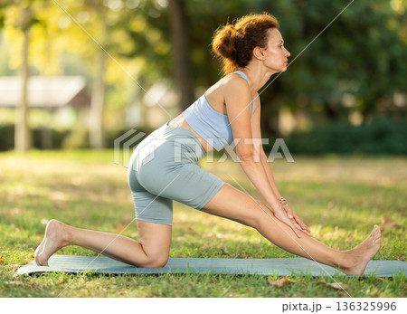 Slim woman practicing yoga - virabhadrasana pose in summer park 136325996