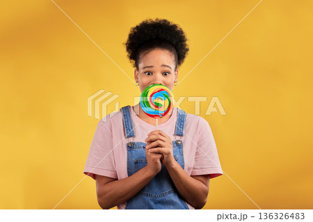 Portrait, black woman with candy or lollipop in studio on yellow background and eating sweets, dessert or food with sugar. Gen z, face of girl and hungry for delicious treats, snack or product Portrait, black woman with candy or lollipop in studio on yellow background and eating sweets, dessert or food with sugar. Gen z, face of girl and hungry for delicious treats, snack or product 136326483