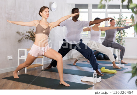 Young woman doing pilates in group in studio 136326484