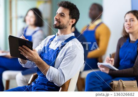 Young man worker listening to lecture and taking notes on tablet Young man worker listening to lecture and taking notes on tablet 136326682